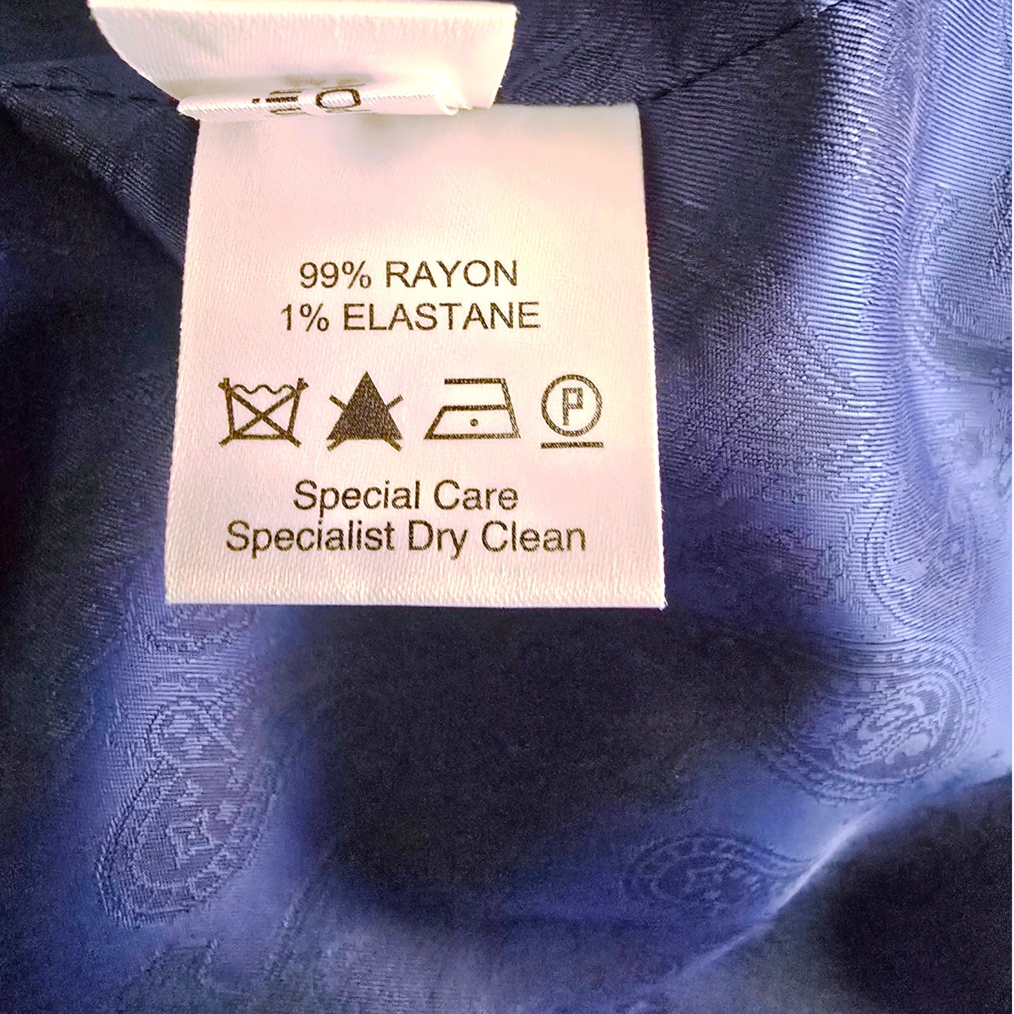 Care label on a blue fabric with text and symbols.
