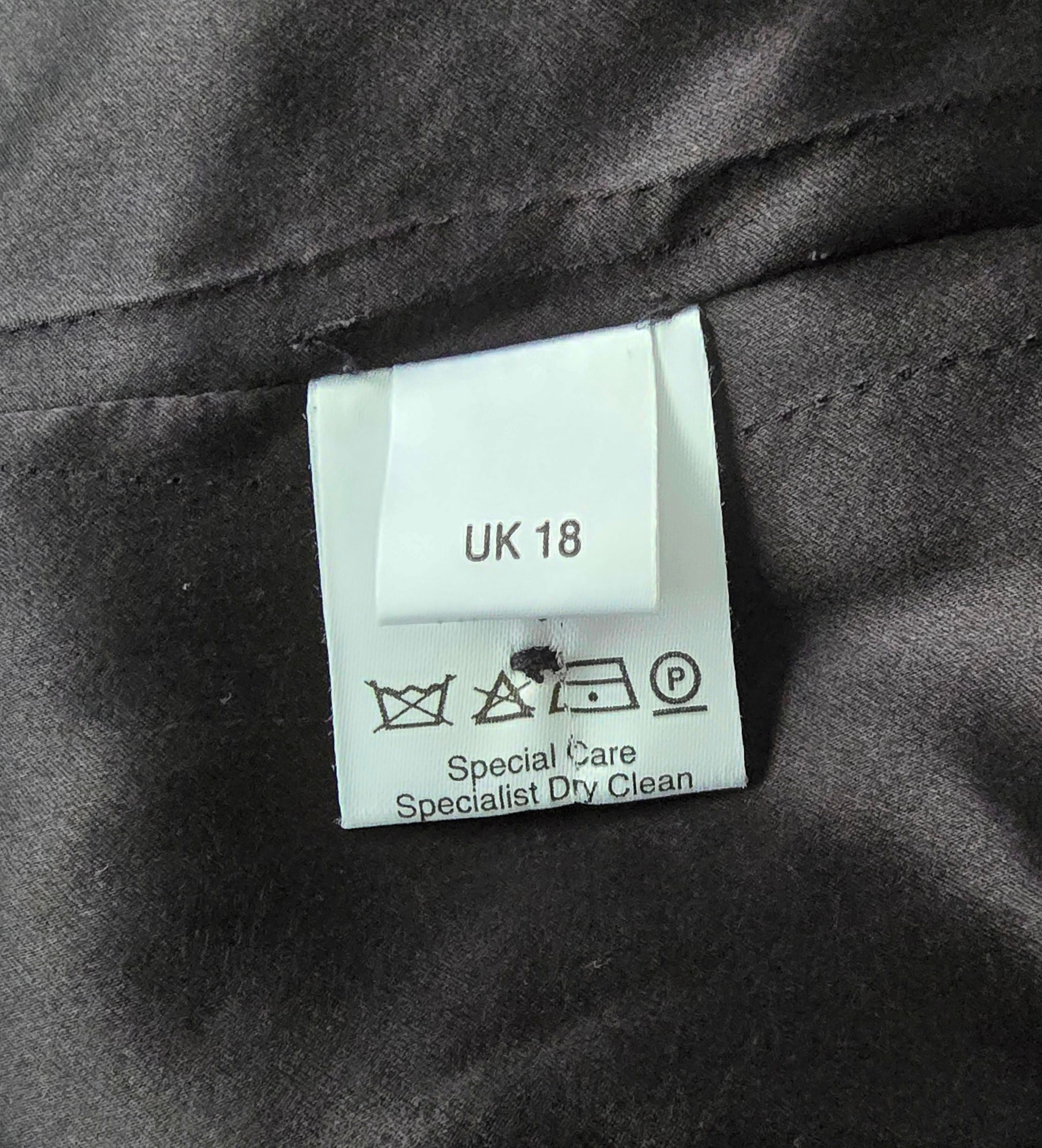 Label showing fabric details and care instructions on black background