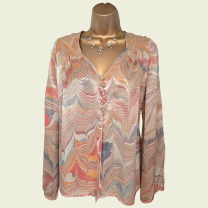 Mannequin wearing a patterned blouse with long sleeves on a plain background