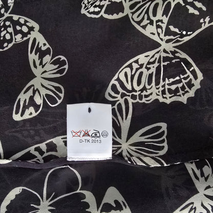 Black fabric with white butterfly patterns and a tag displaying text and symbols.