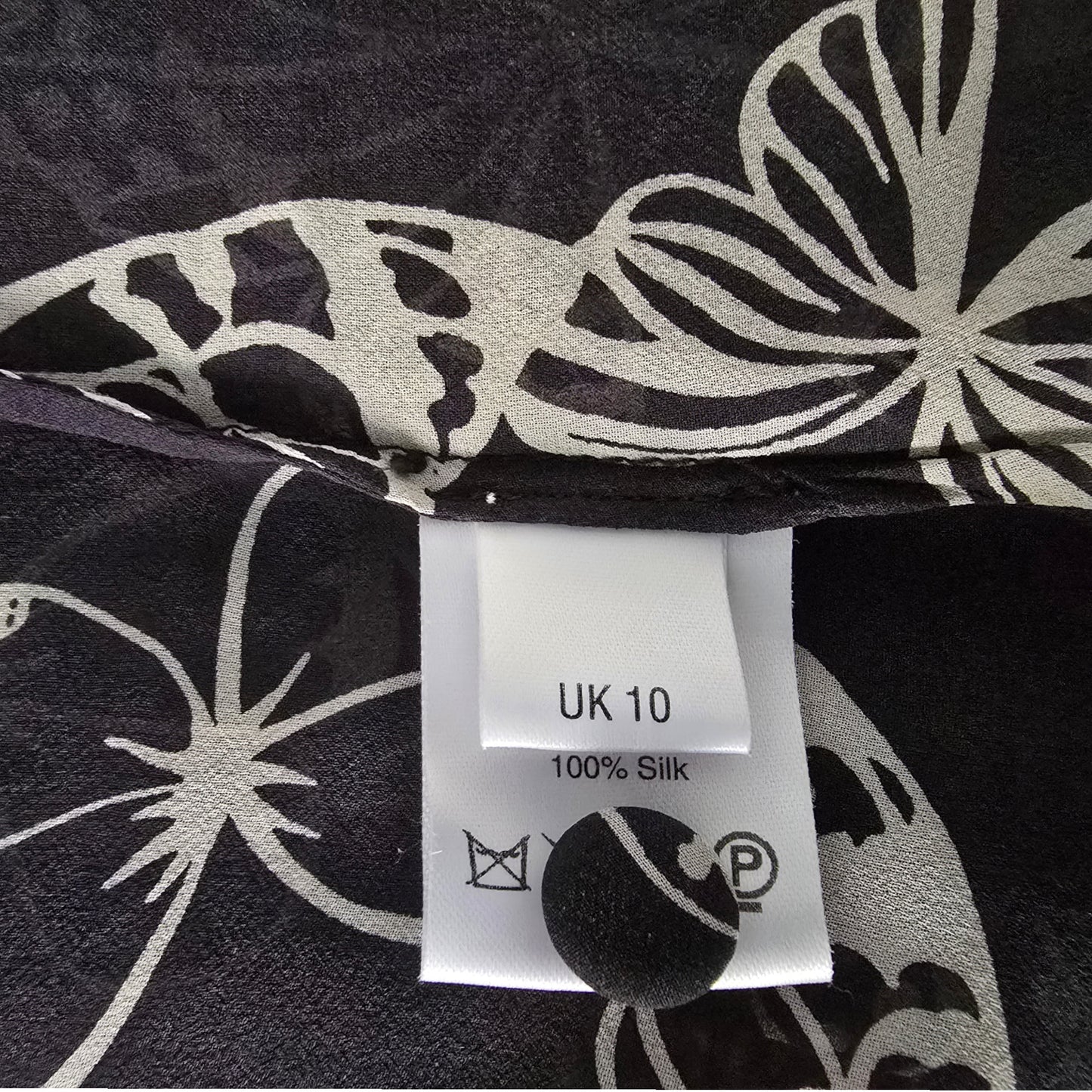Black fabric with white butterfly patterns and a label indicating UK size 10 and 100% silk.