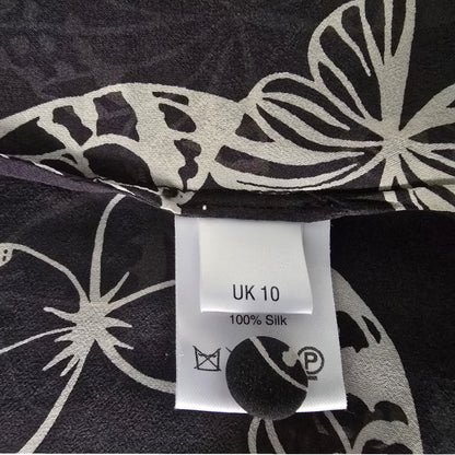 Black fabric with white butterfly patterns and a label indicating UK size 10 and 100% silk.