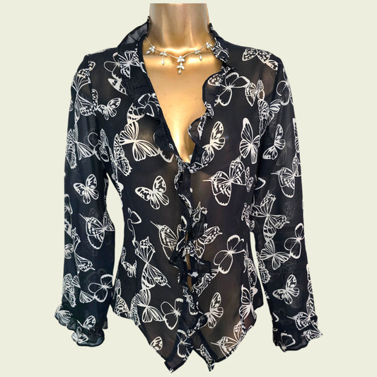 Black blouse with white butterfly patterns on a mannequin against a plain background
