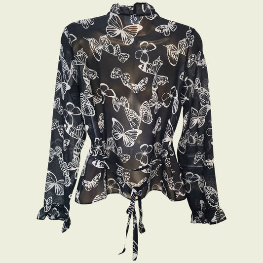 Black blouse with white butterfly pattern on a beige background