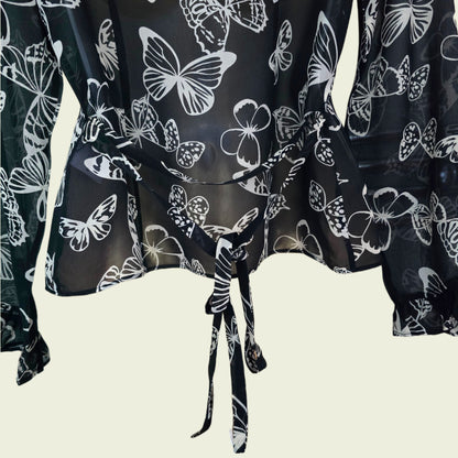 Black blouse with white butterfly patterns on a beige background