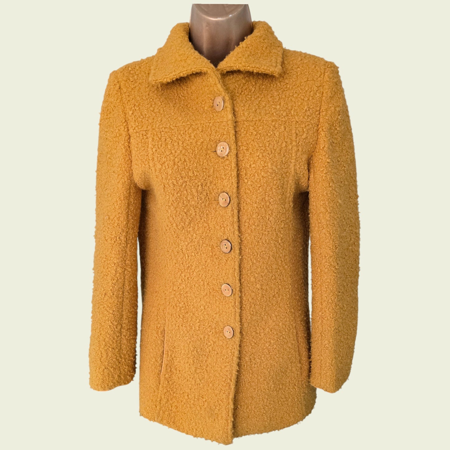 Mannequin wearing mustard coloured jacket on beige background