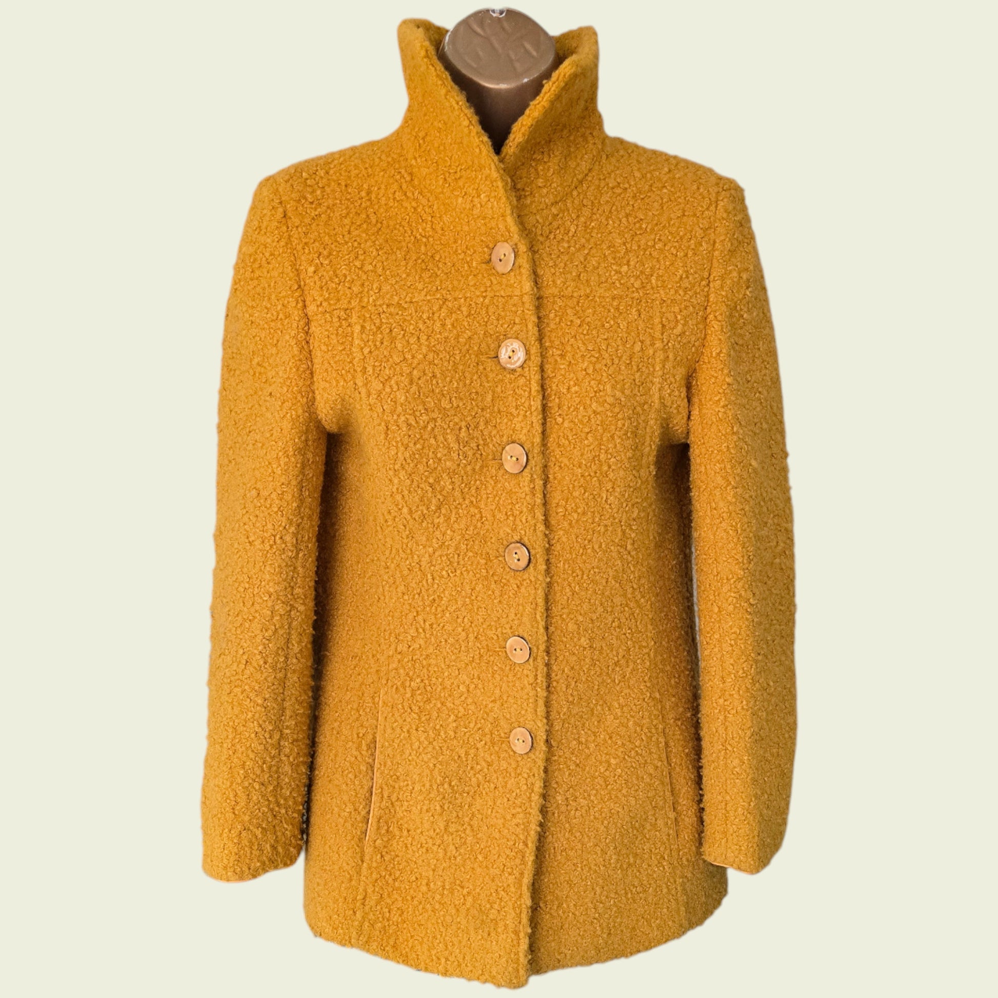 Mannequin wearing mustard coloured jacket on beige background