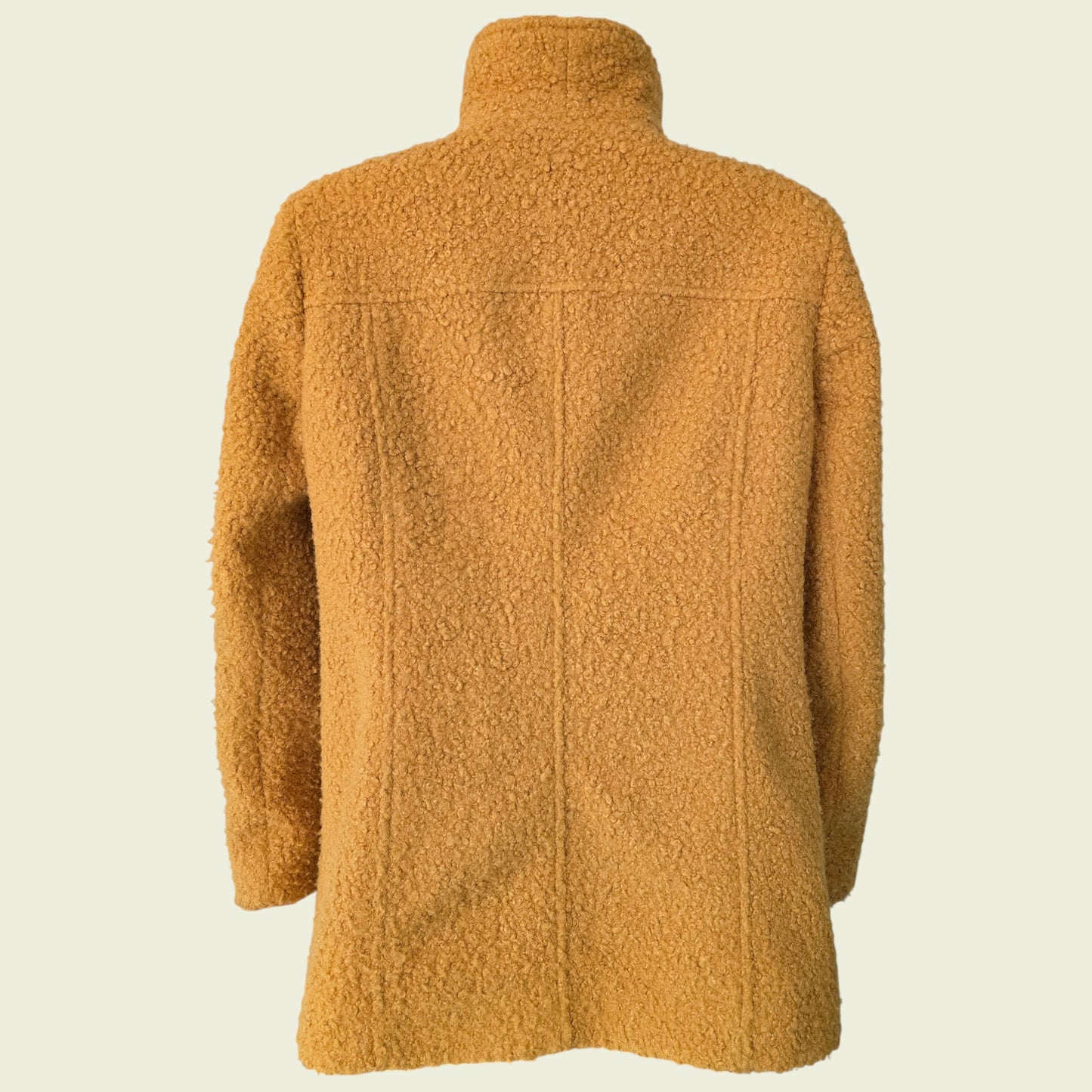 Mannequin wearing mustard coloured jacket on beige background