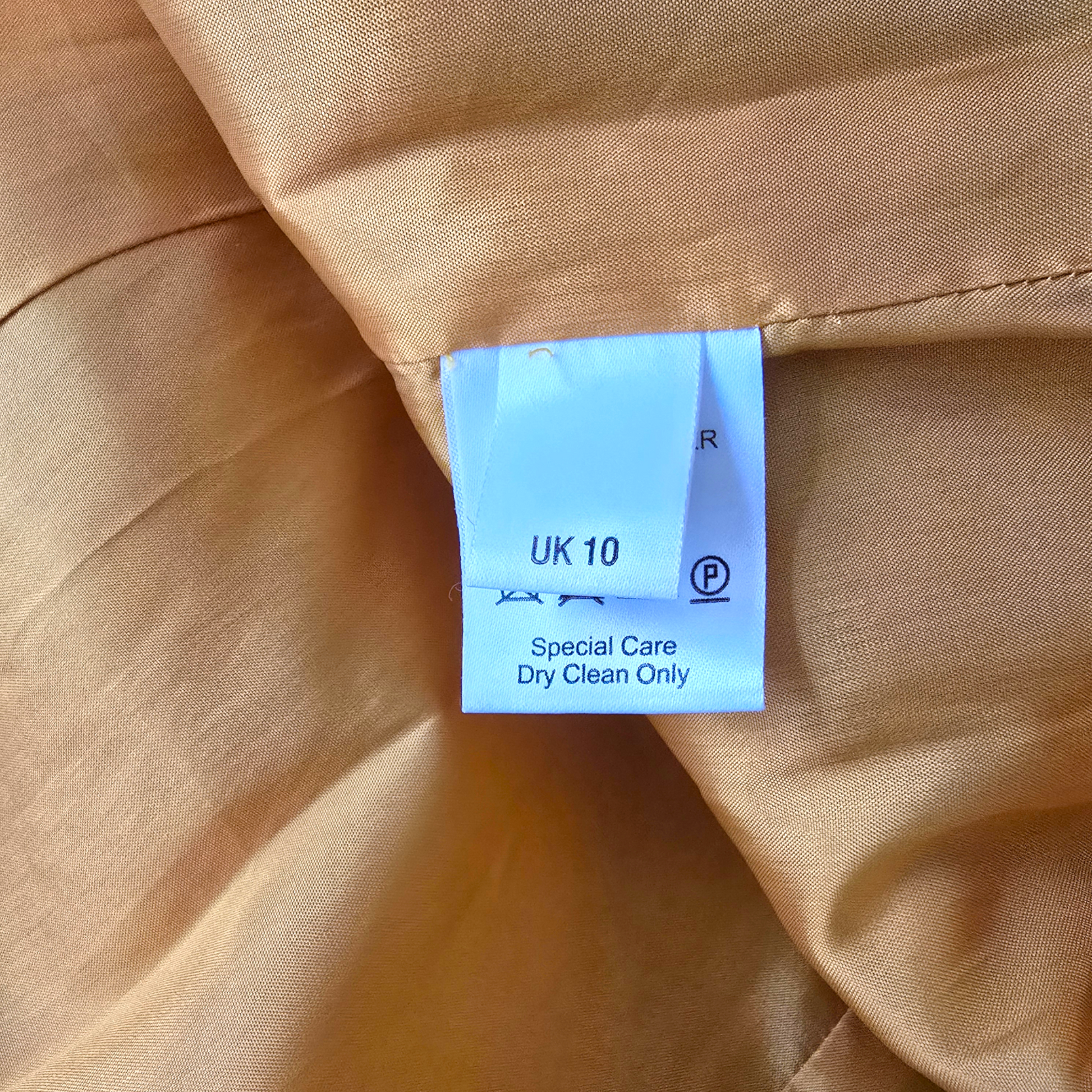 Clothing tag on a beige fabric with 'Special Care Dry Clean Only' label.
