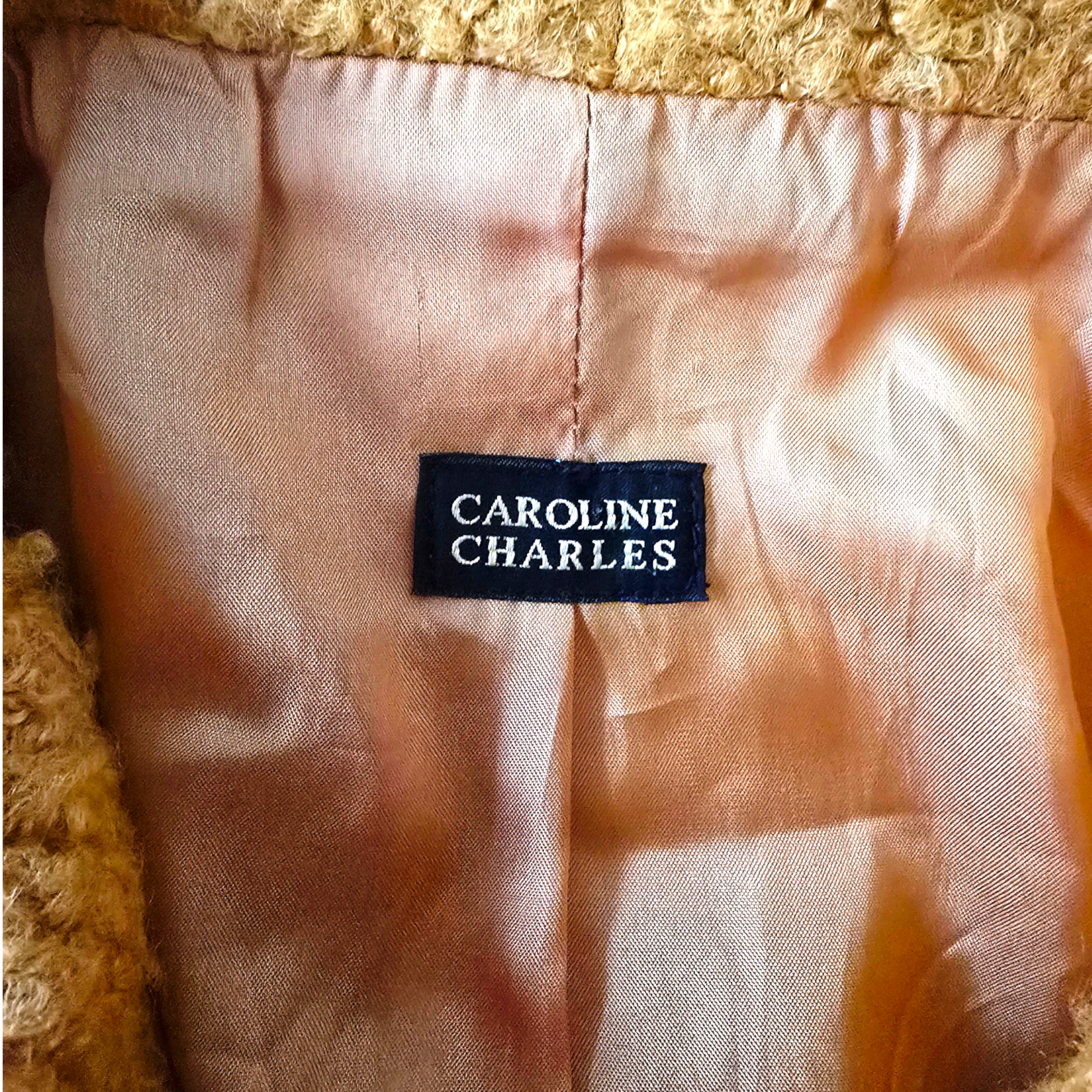 Clothing label with 'Caroline Charles' on a textured fabric background