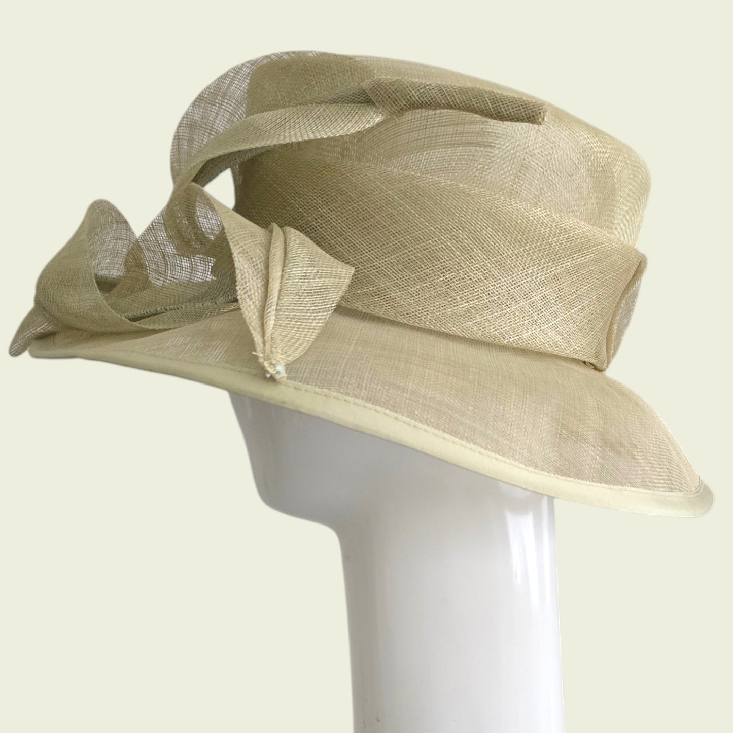 Beige hat with decorative bow on a mannequin head against a light background