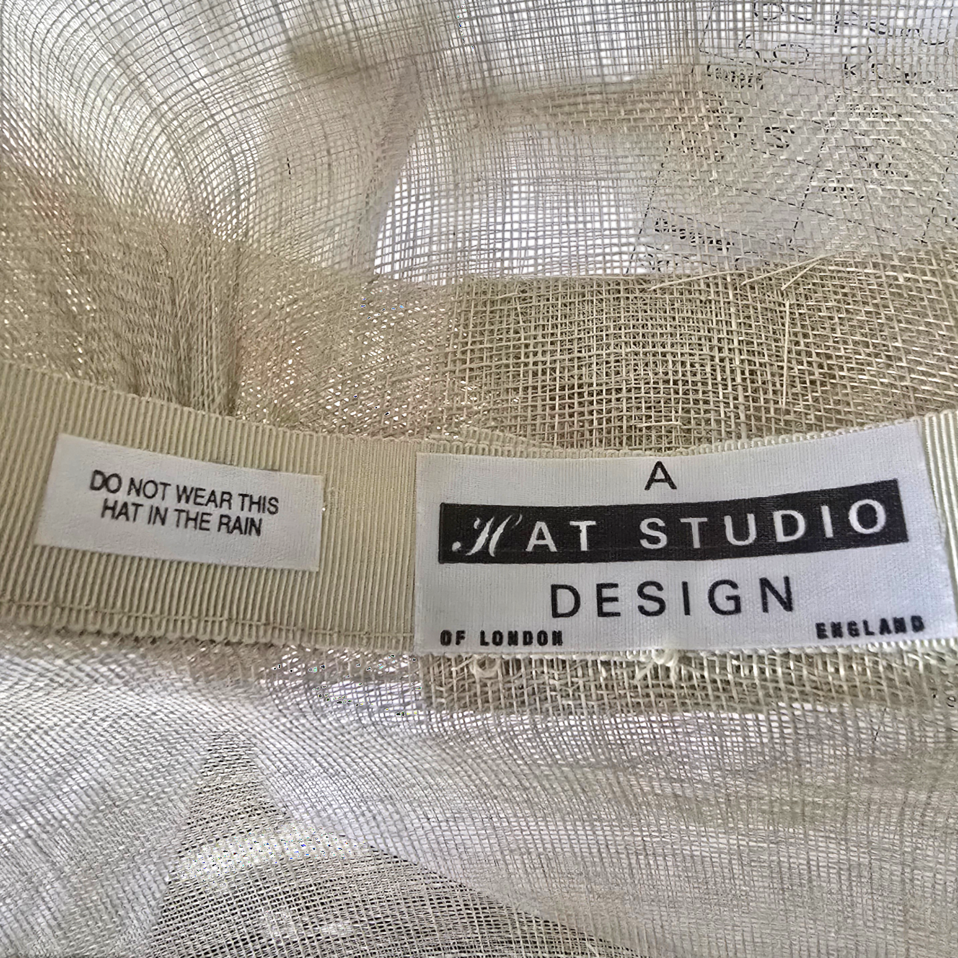 Close-up of a hat with 'A Hat Studio Design' label and warning tag.