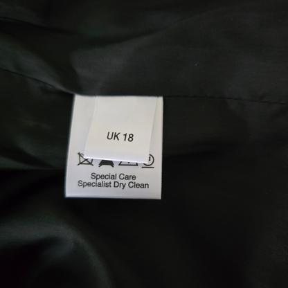 Clothing label on a dark fabric background with 'UK 18' and 'Specialist Dry Clean' text.
