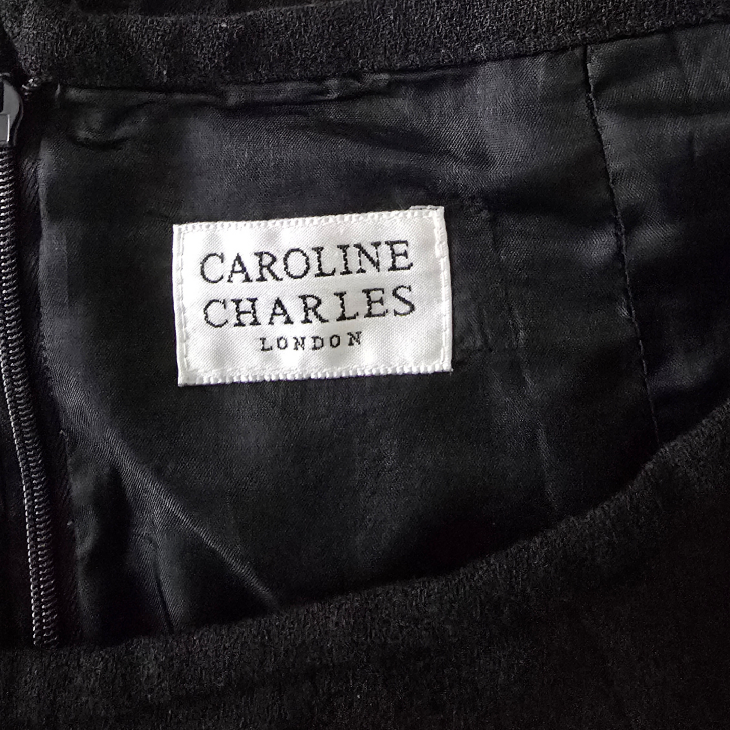 Label with 'Caroline Charles London' on a black fabric background