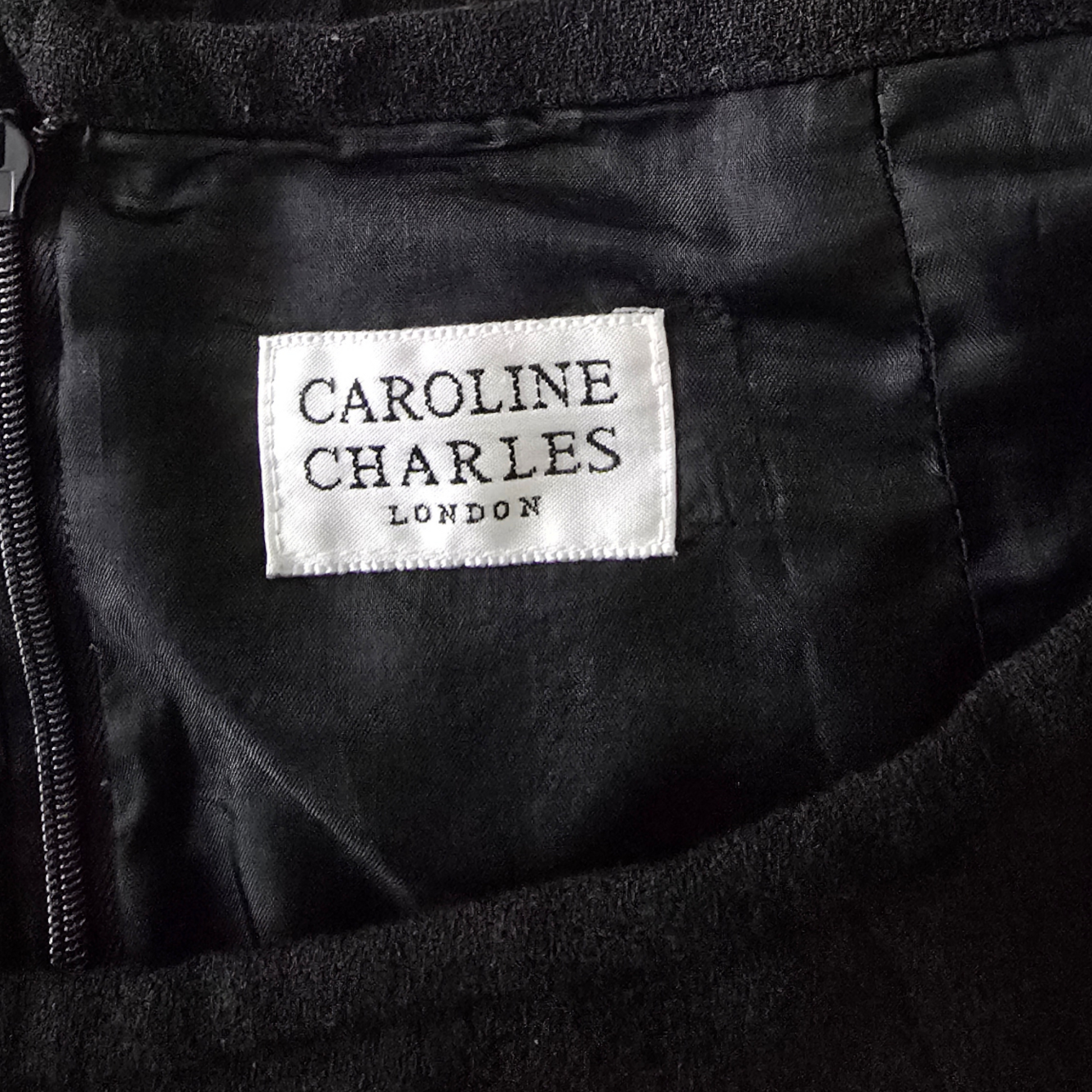 Label with 'Caroline Charles London' on a black fabric background
