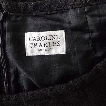 Label with 'Caroline Charles London' on a black fabric background