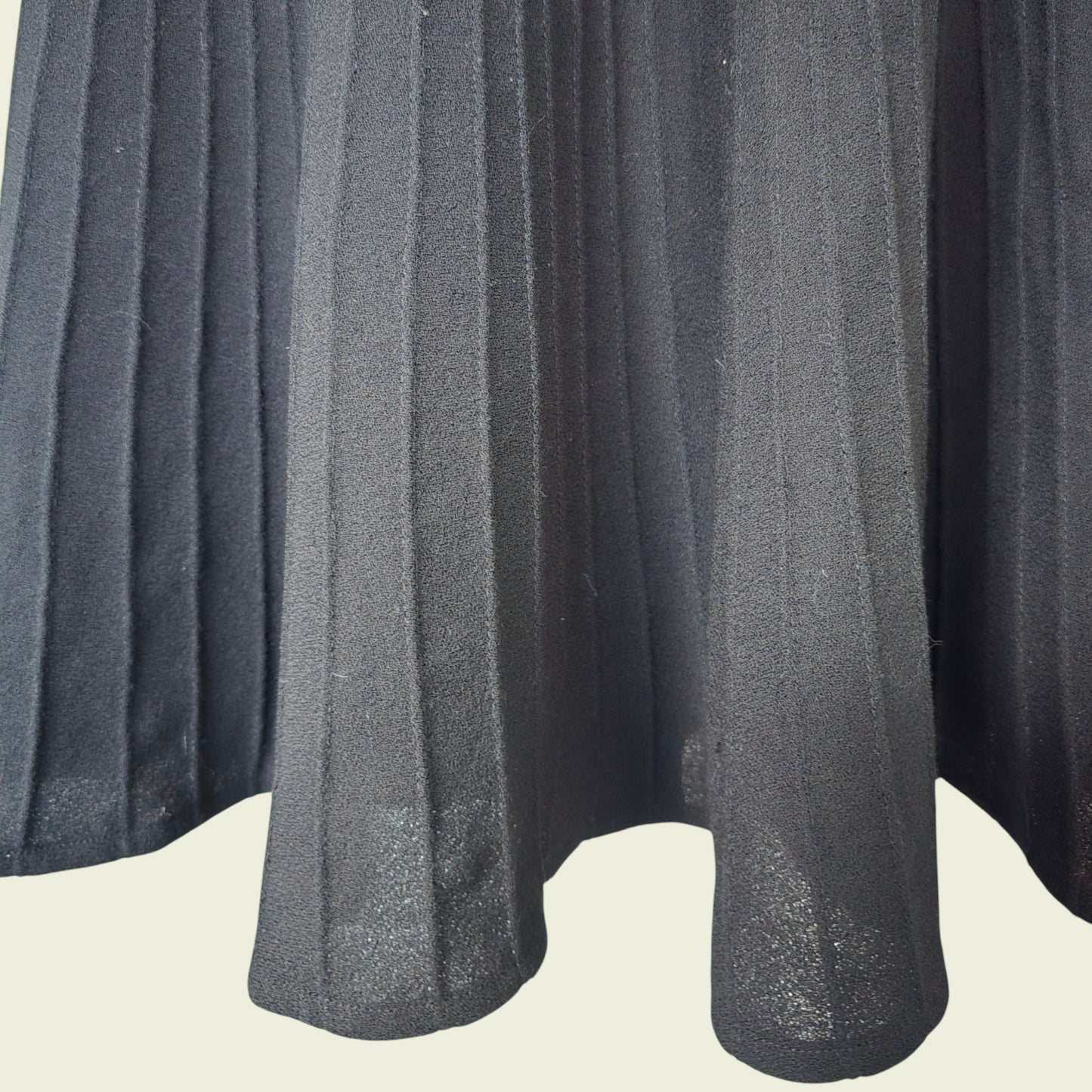 Close-up of a pleated black fabric skirt on a light background