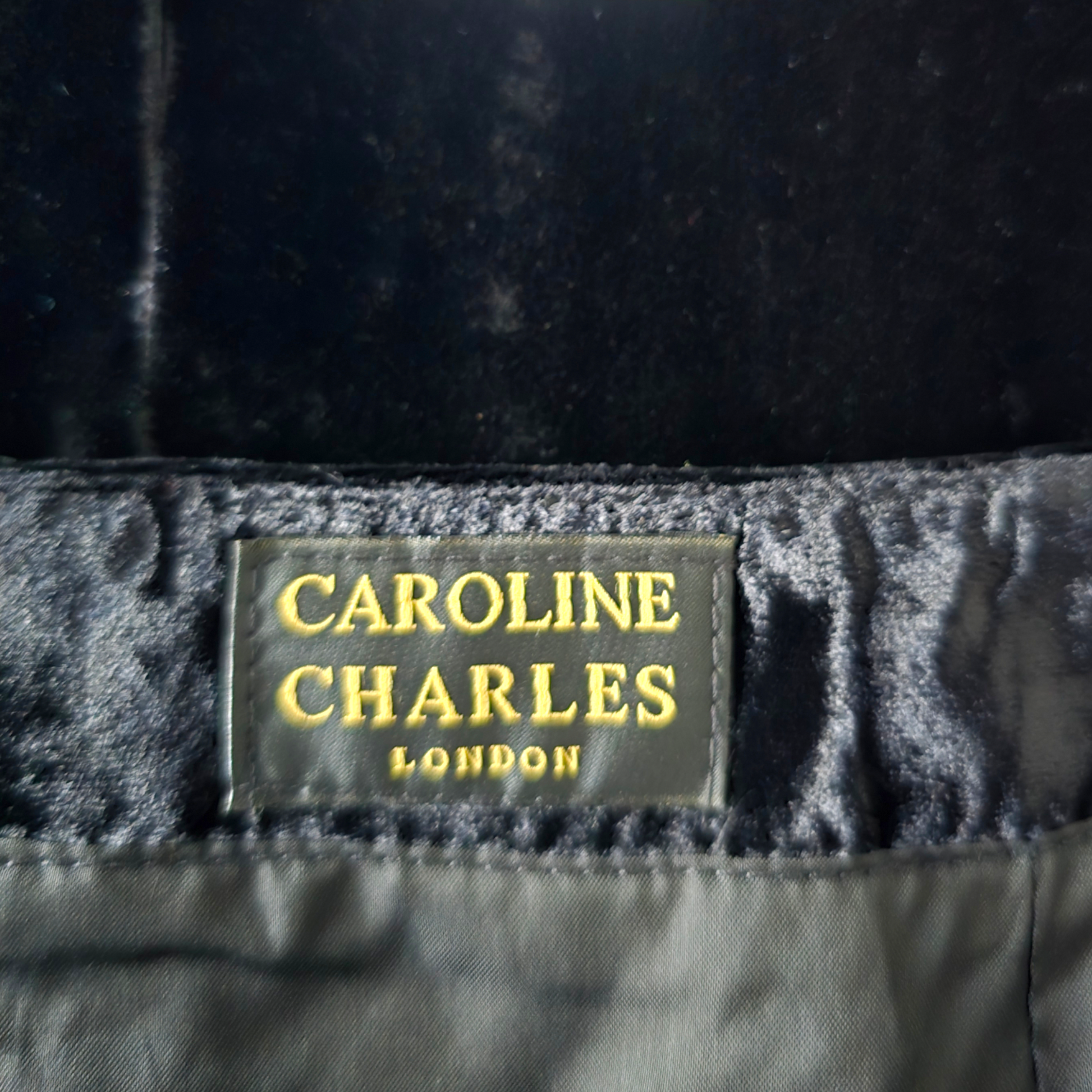 Label with 'Caroline Charles London' on a dark fabric background