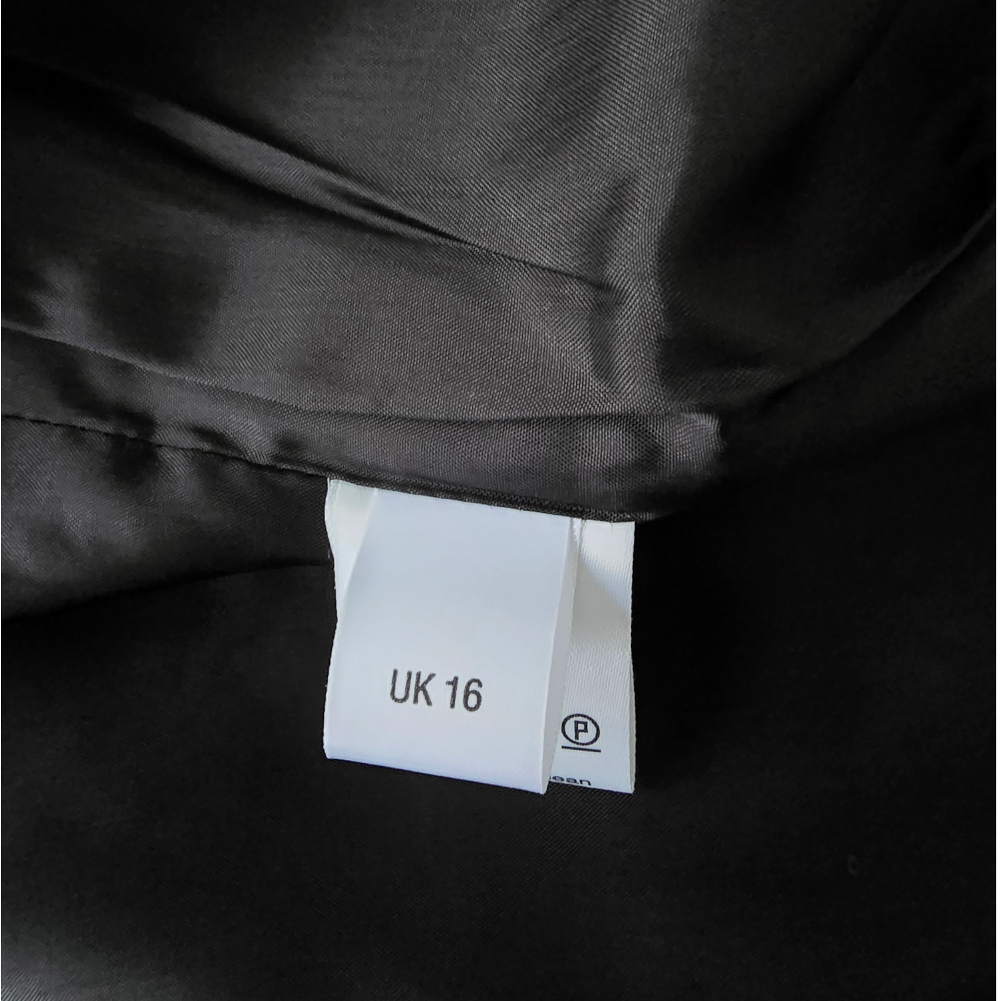 Black fabric with a white tag displaying 'UK 16' on a black background