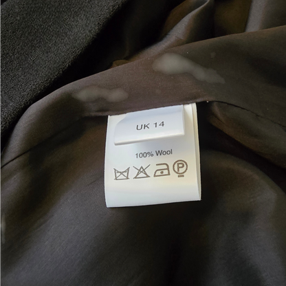 Clothing label on a brown garment with size 'UK 14' and material '100% Wool'.