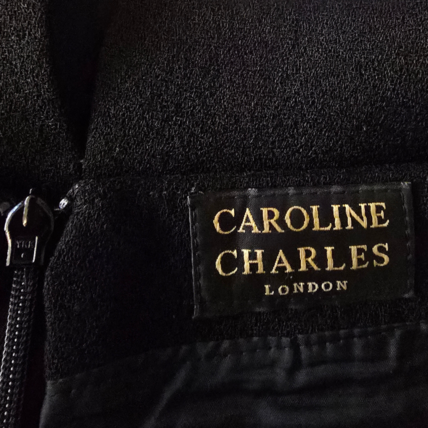 Close-up of a Caroline Charles London label on a black garment.