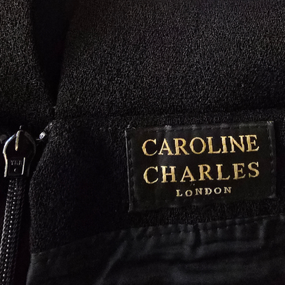 Close-up of a Caroline Charles London label on a black garment.