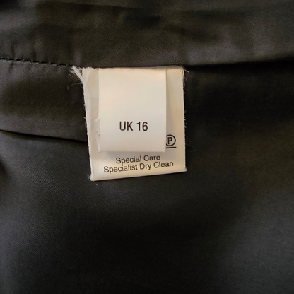 Clothing label on a black garment with size 'UK 16' and care instructions.