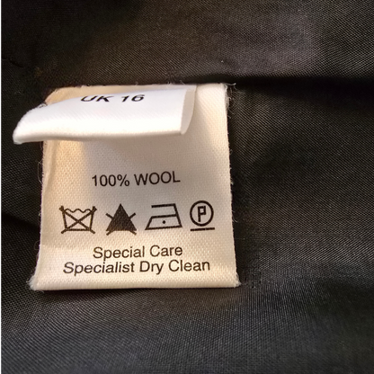 Clothing label with wool content and care instructions on a dark fabric background