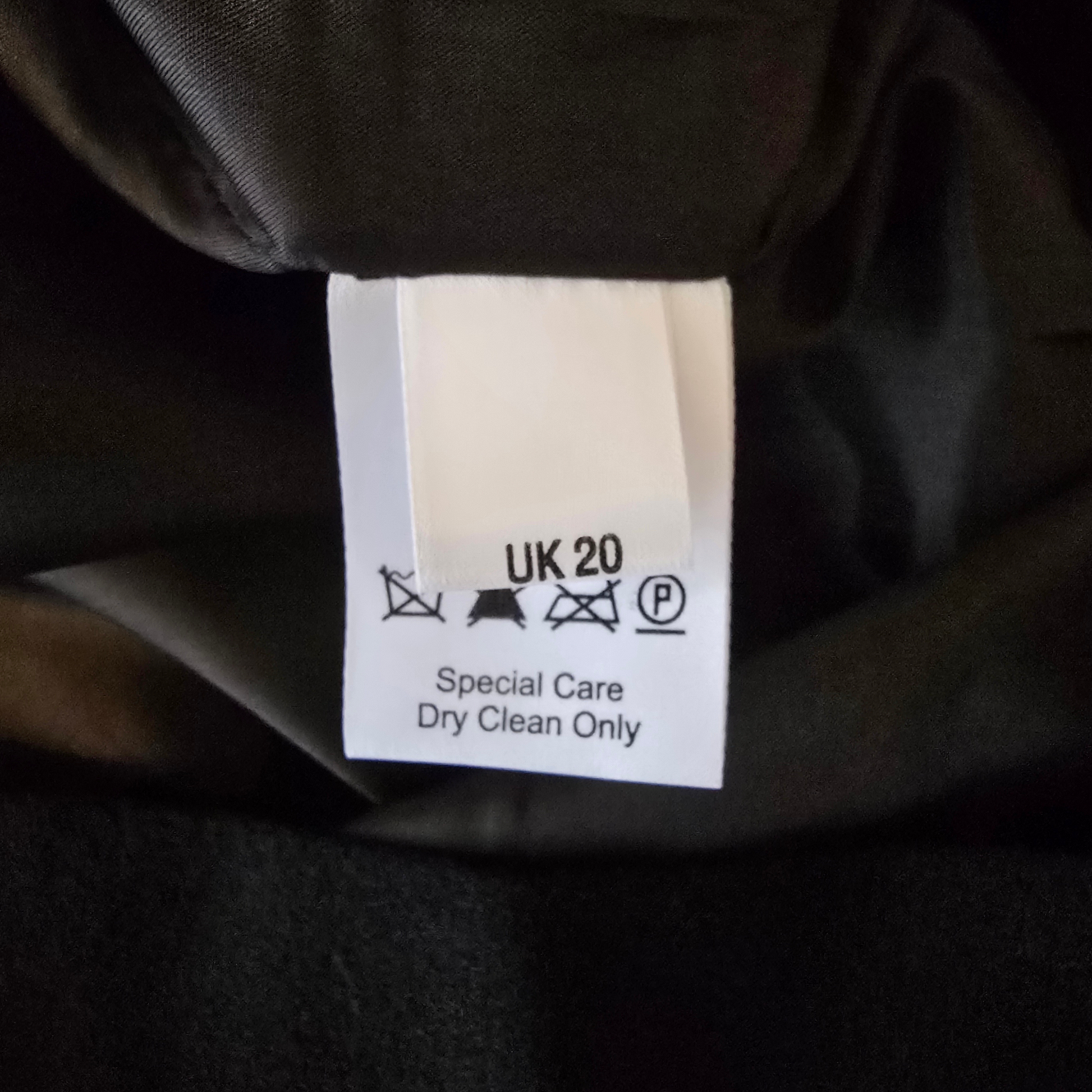 Clothing label on a dark fabric background with care instructions.