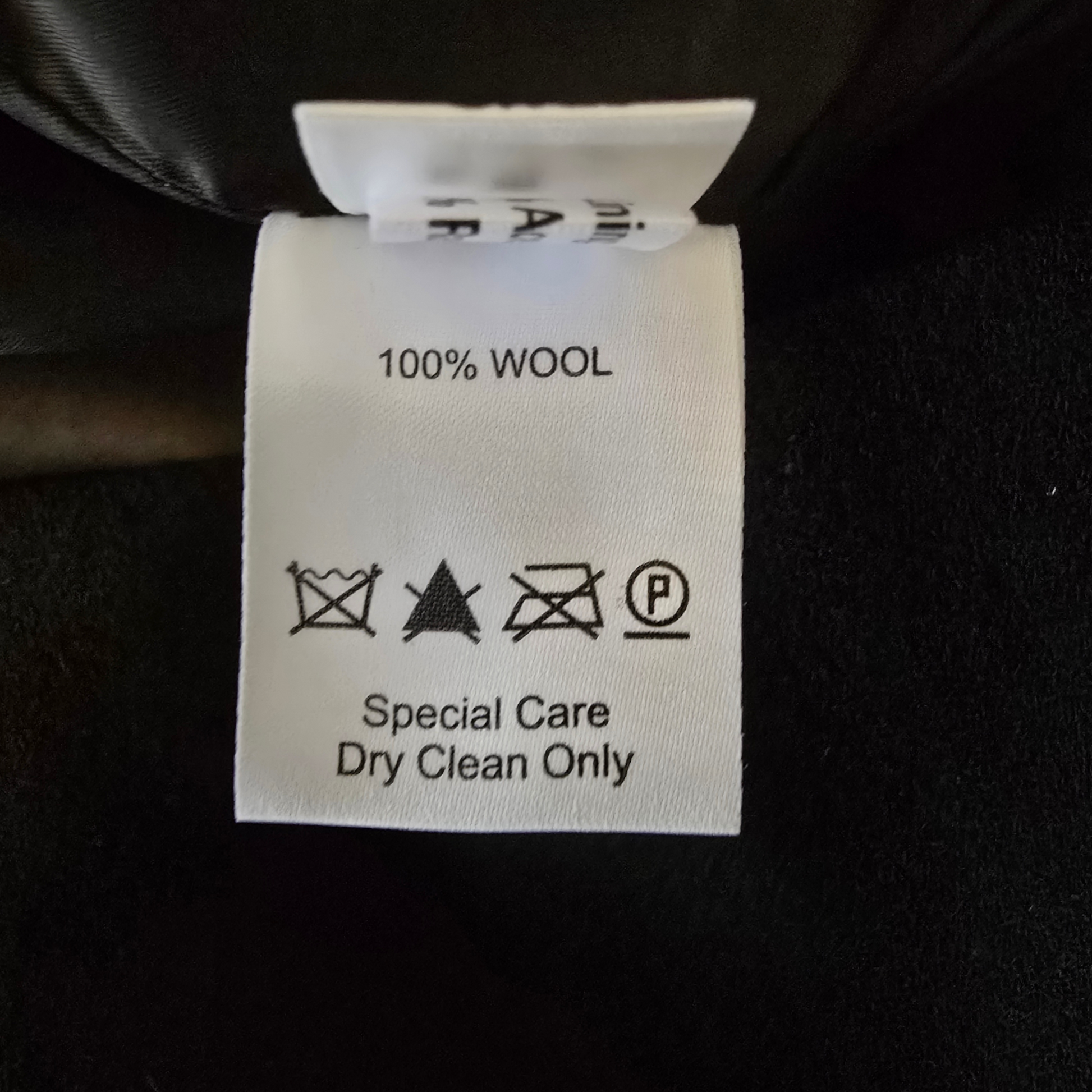 Wool label on a black fabric background with care instructions.