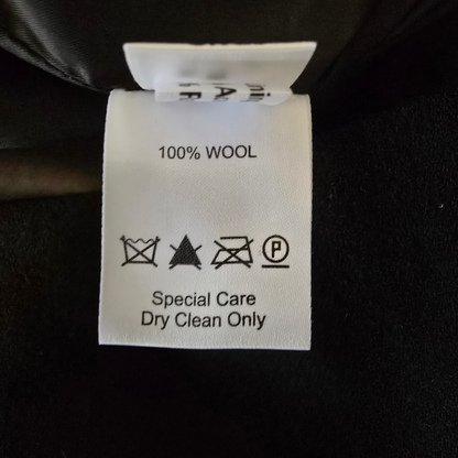 Wool label on a black fabric background with care instructions.