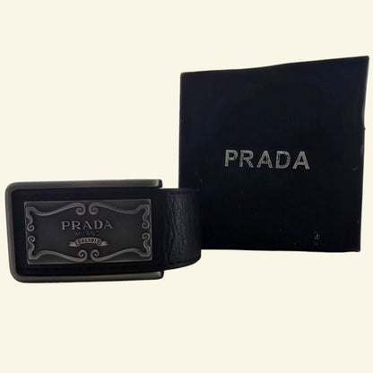 Black Prada belt buckle and box on a beige background
