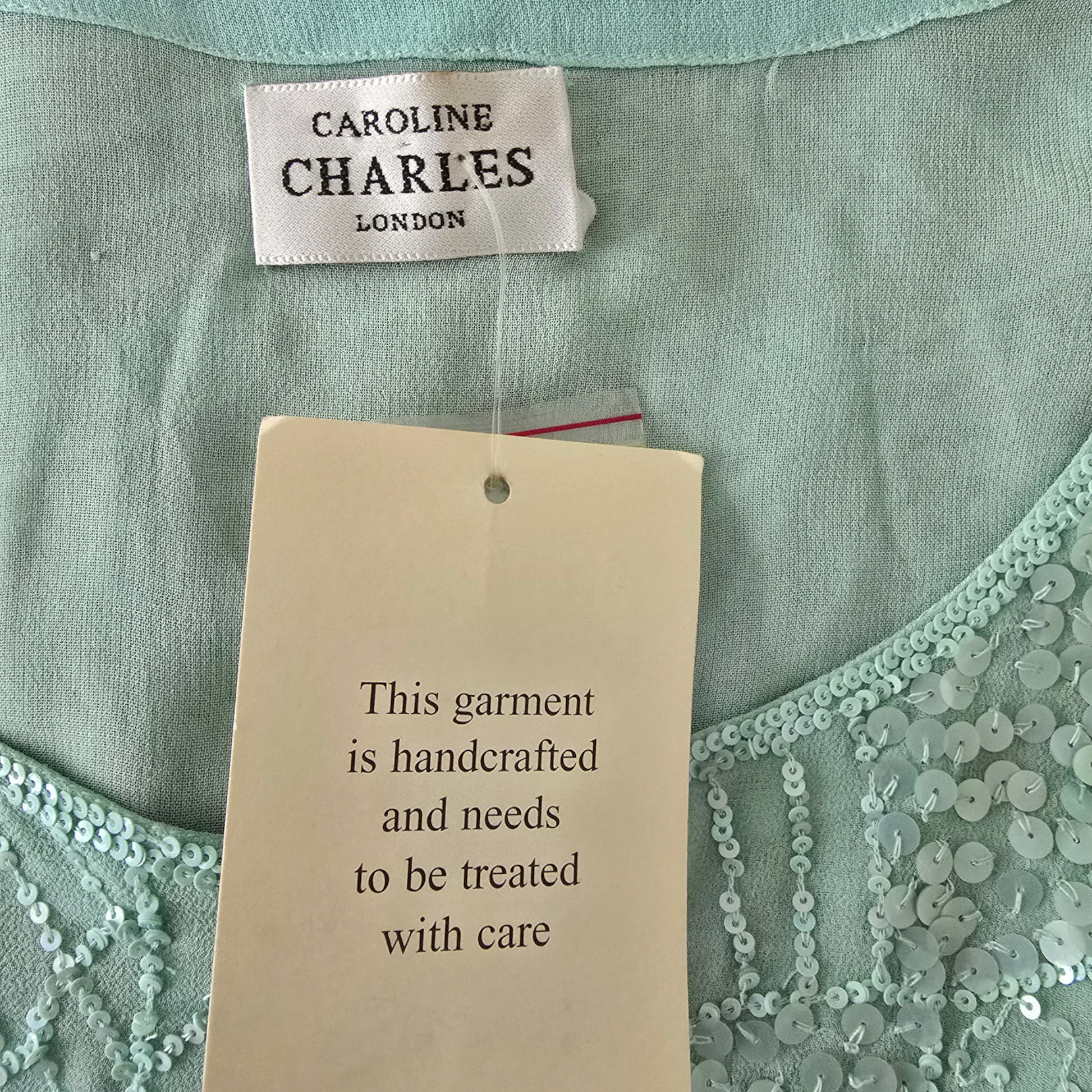 Light green garment with 'Caroline Charles London' label and care instruction tag.