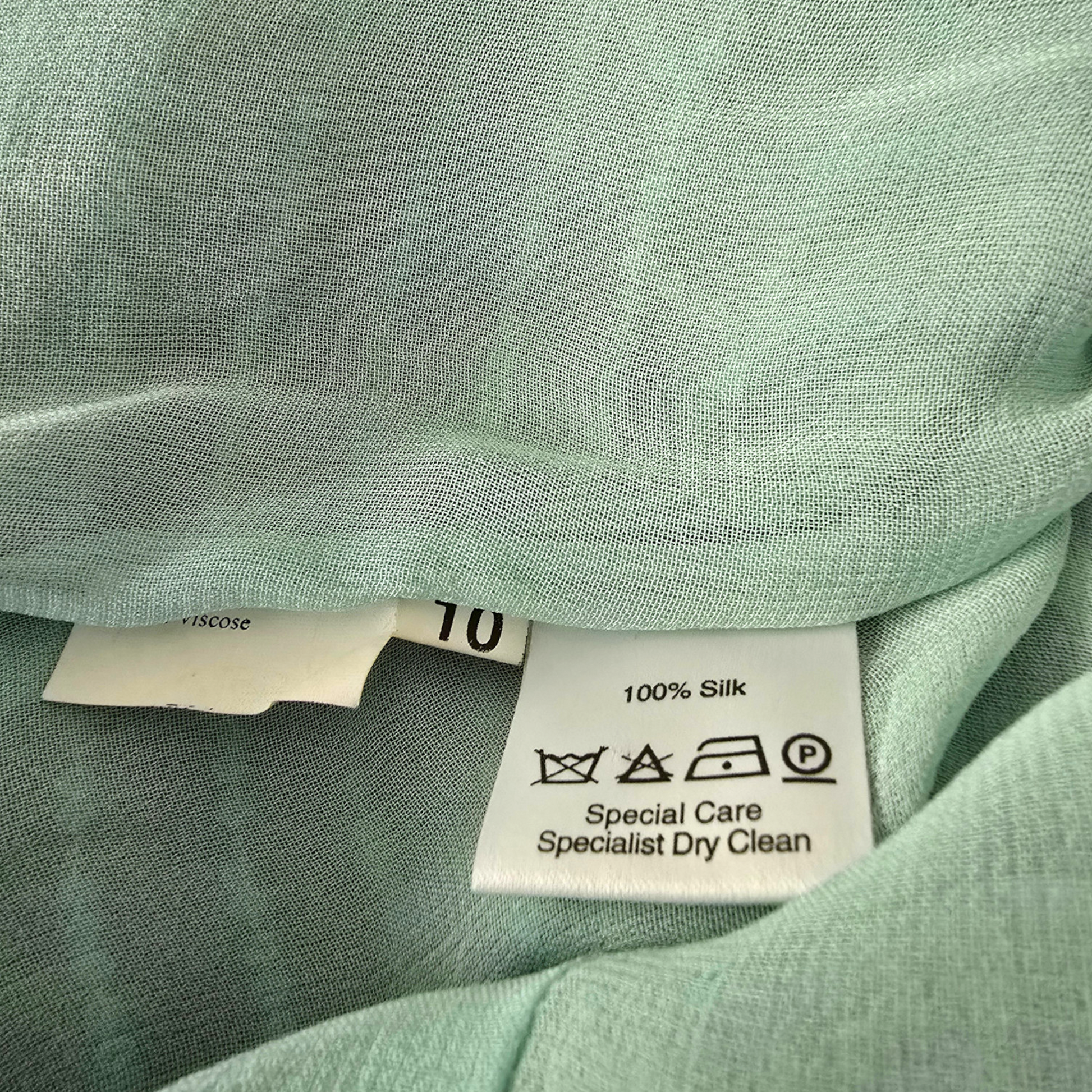 Close-up of a green fabric with a care label on a light green background