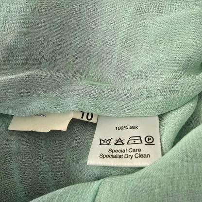 Close-up of a green fabric with a care label on a light green background