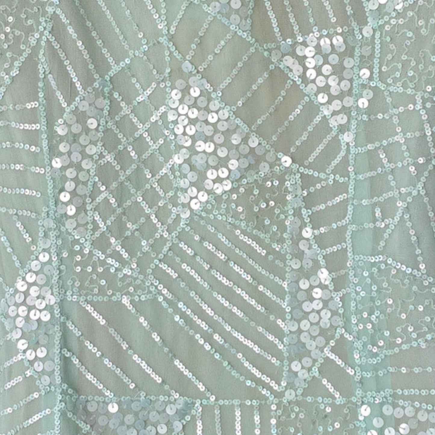 Close-up of a fabric with a geometric pattern and sequins on a light green background