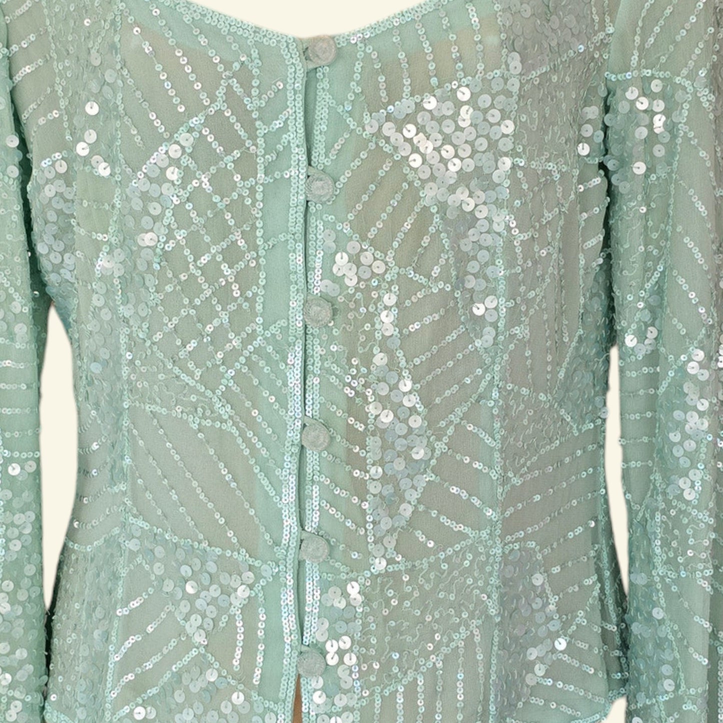 Mint green sequin blouse with buttons on a plain background