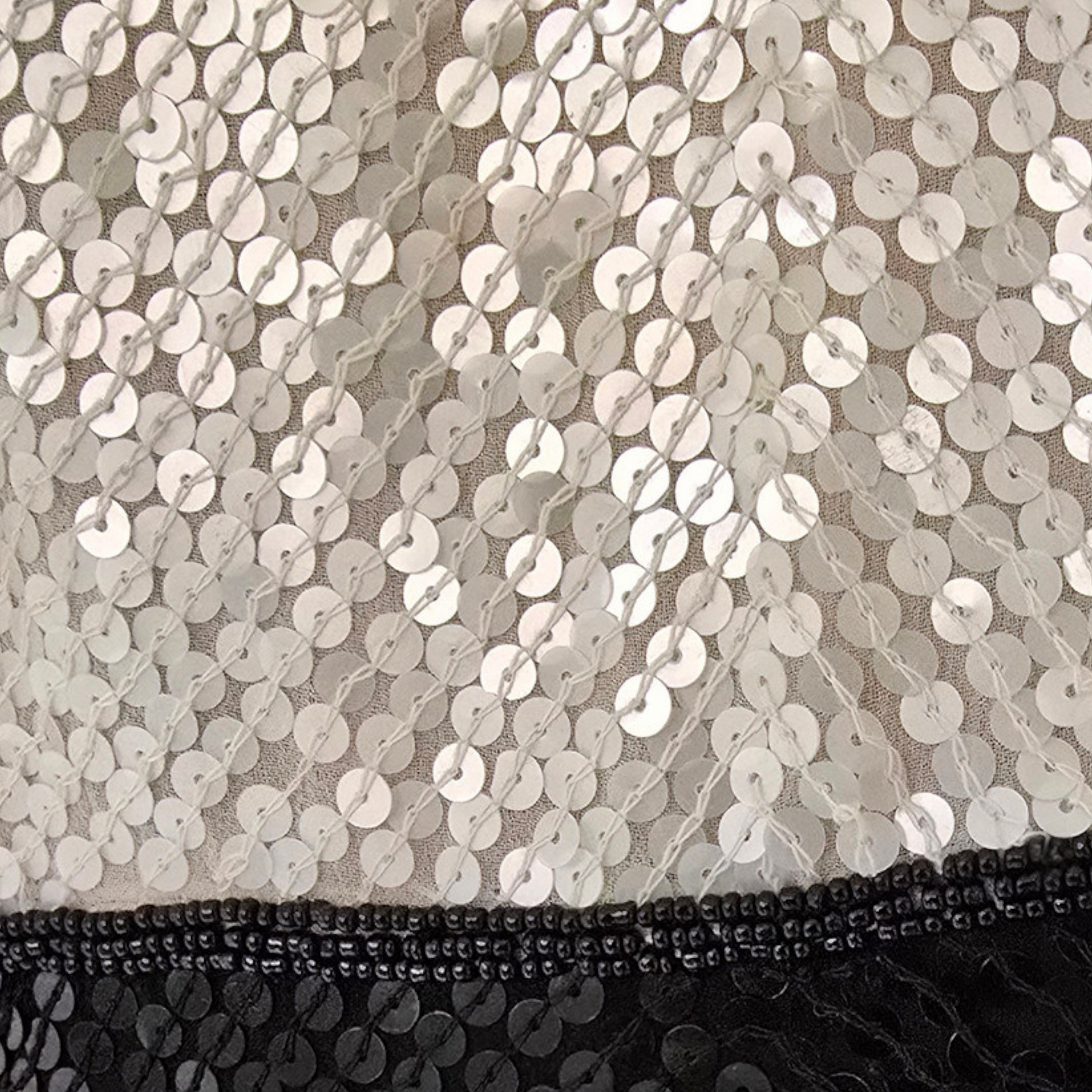 Close-up of sequined fabric with a mix of silver and black colors.