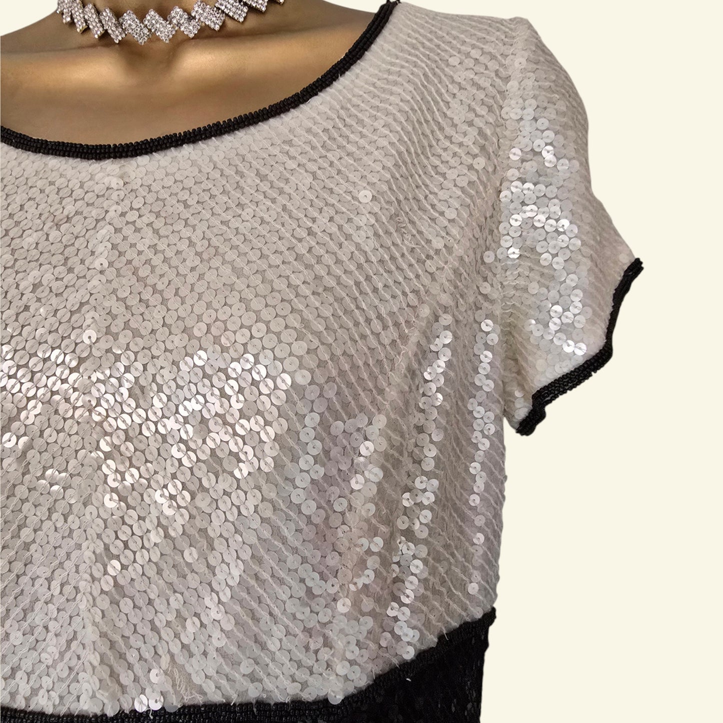 Sequined top with black trim on a white background