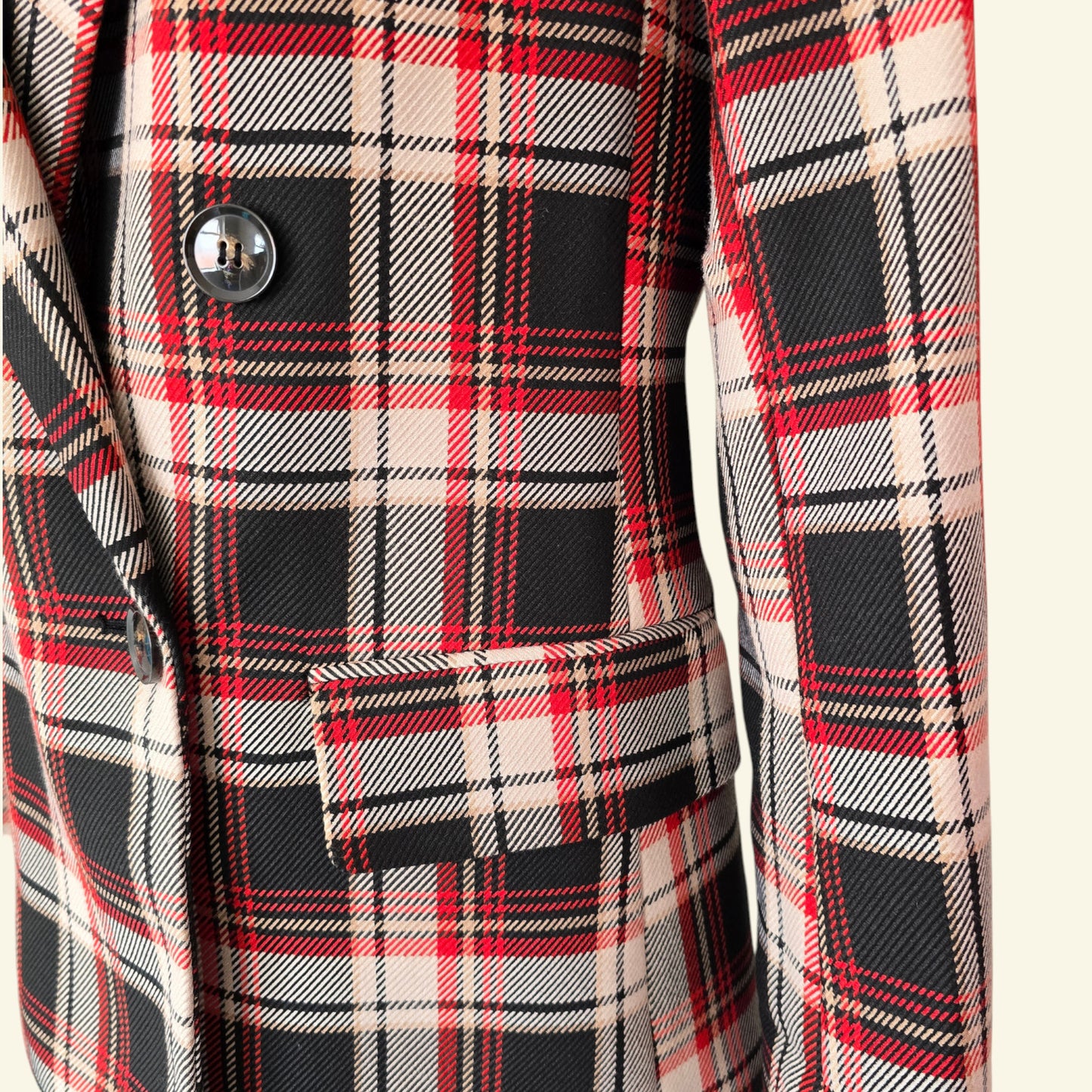 Close-up of a plaid coat with red, black, and beige pattern.