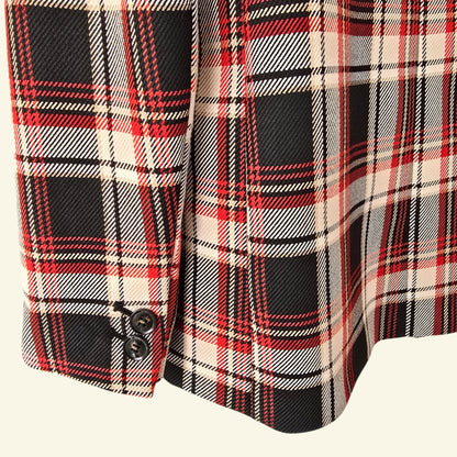 Close-up of a plaid fabric with red, black, and beige colors on a white background.