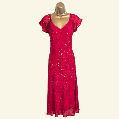 A bright pink sequined lace midi dress with short flutter sleeves and a V-neckline, displayed on a gold mannequin torso against a light cream background.