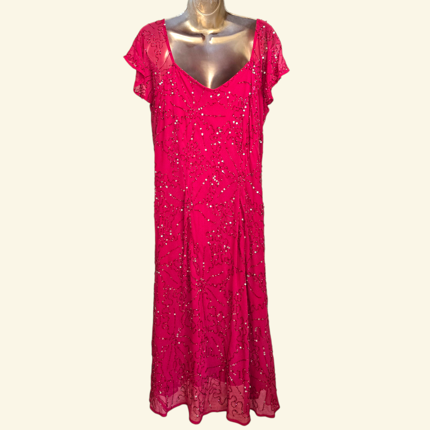 A bright pink dress with short flutter sleeves,  and all-over sequin embellishment, displayed on a metallic mannequin against a light cream background.