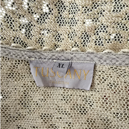 Close-up of a beige fabric with size tag reading TUSCANY COLLECTION and XL, showing the interior neckline and textured lace-like fabric.