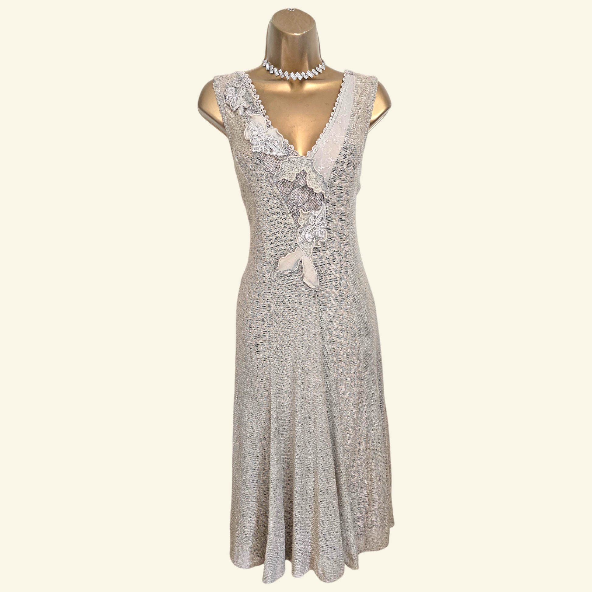 A sleeveless light gray lace dress with a V-neckline and decorative lace applique, displayed on a gold mannequin torso against a plain cream background.