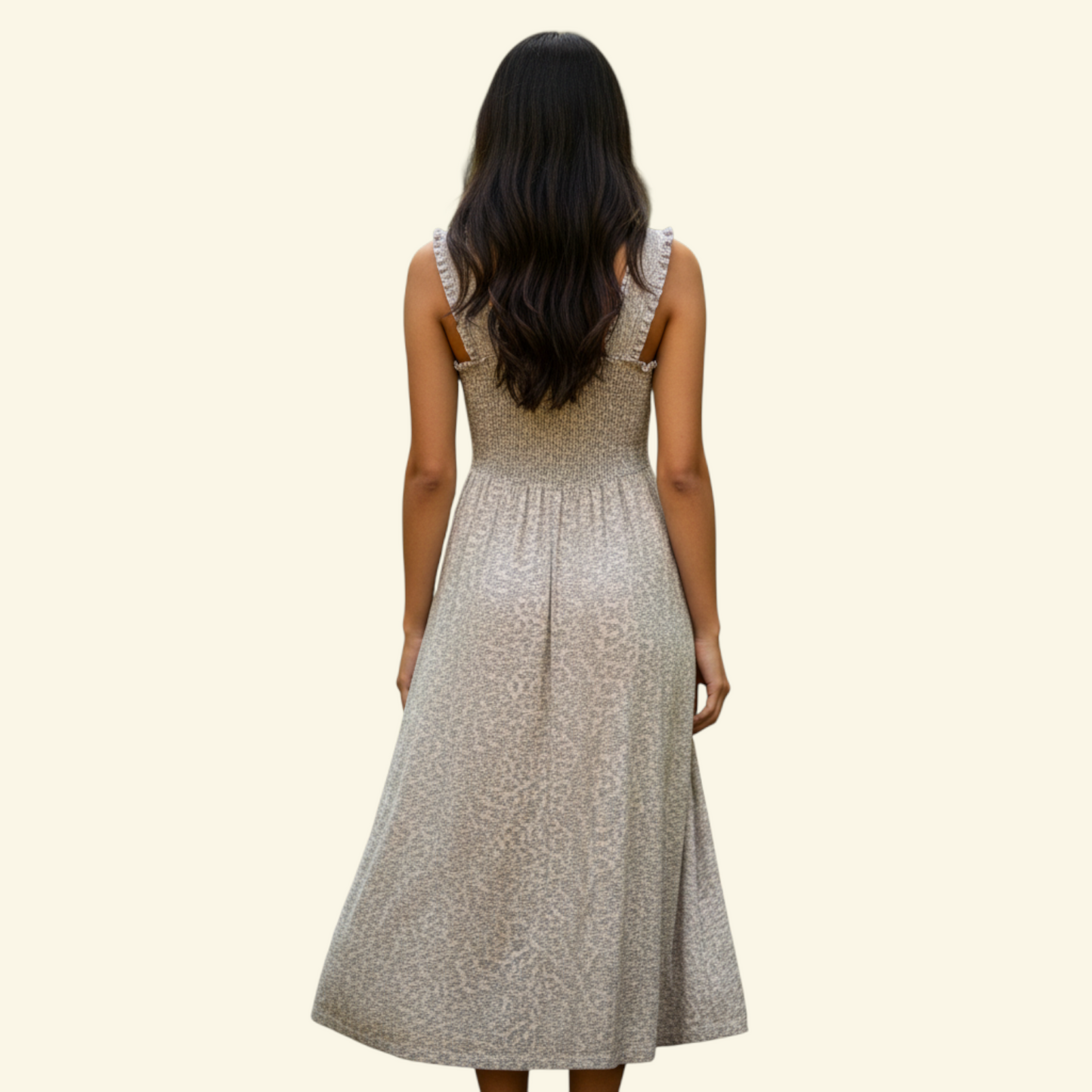 A woman viewed from behind wearing a sleeveless midi dress with a textured beige pattern, set against a solid cream background.