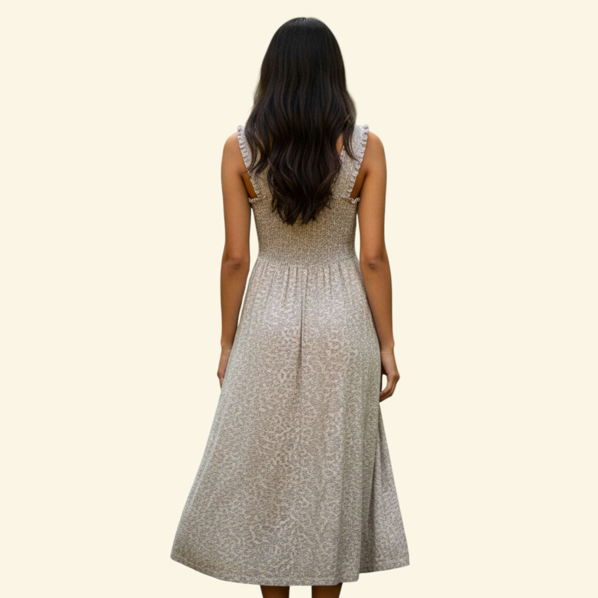 A woman viewed from behind wearing a sleeveless midi dress with a textured beige pattern, set against a solid cream background.