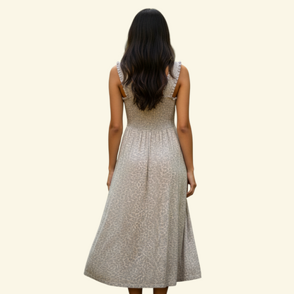 A woman viewed from behind wearing a sleeveless midi dress with a textured beige pattern, set against a solid cream background.