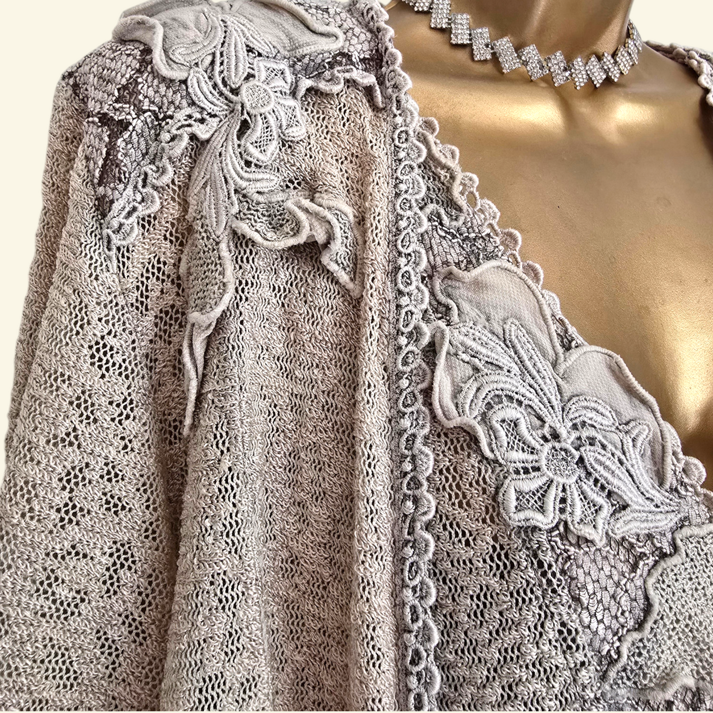 A close-up of a beige lace dress and jacket with embroidered details.