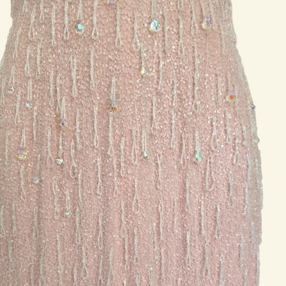 Close up of hand beaded detail on pink dress on beige background